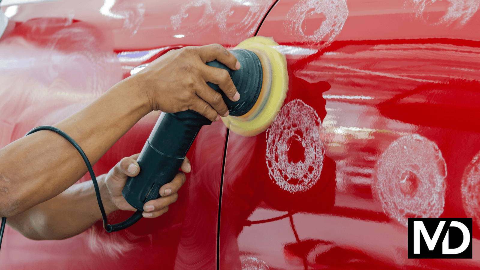 a person holding a machine with a yellow object on the side of a red car